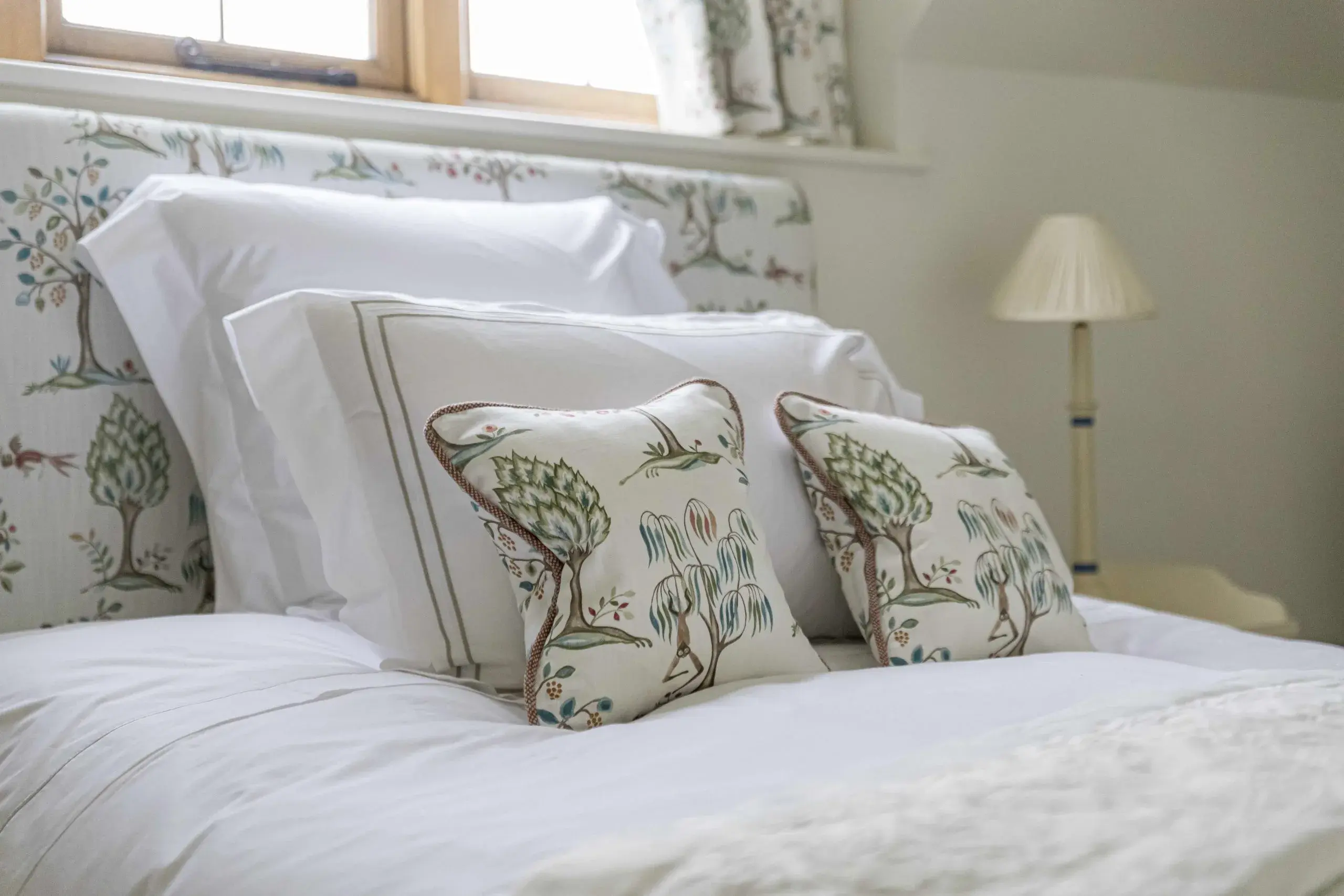 Bedroom with botanical headboard and tree-print cushions